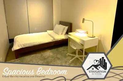 a small bedroom with a bed and a desk at Luxurious 2 Bedroom Family Suite plus Maid Rm in Eastwood City in Manila