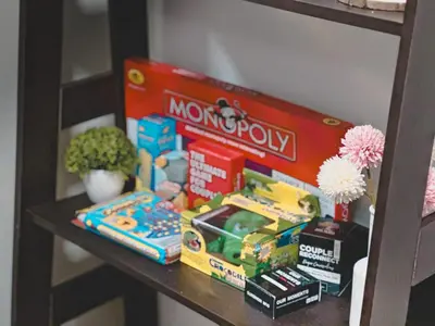 a shelf with toys and a box of monopoly on it at Apartment Condo in Air Residences Makati wifi Netflix Disney, pool & mall in Manila