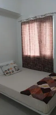 a bed in a room with a window with a blanket at BCP Homes in Manila