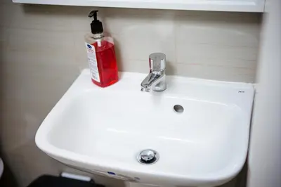 a bathroom sink with a red bottle of soap on it at Tatet Staycation Short Walk to SM MOA in Manila