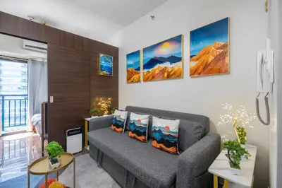 a living room with a couch and paintings on the wall at Newly Turned 0ver Cond0- Air Makati 1BR with Balcony in Manila