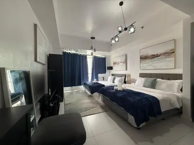 a bedroom with two beds and a chair in it at Family KL Greenbelt Makati in Manila