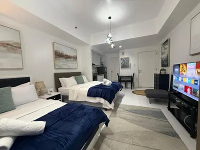 a bedroom with two beds and a flat screen tv at Family KL Greenbelt Makati in Manila