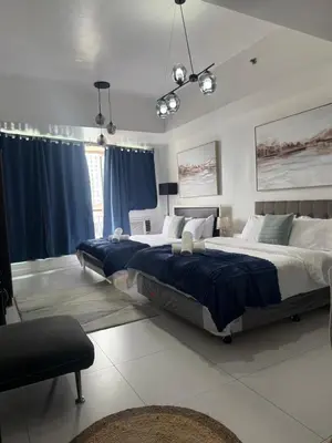 two beds in a bedroom with blue curtains at Family KL Greenbelt Makati in Manila