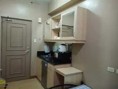 a small kitchen with white cabinets and a door at Budget Condotel in Manila