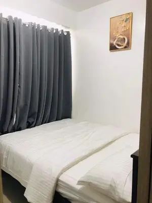 a bedroom with a bed and a window with blue curtains at Shore Residence condotel,Pasay city Philippines in Manila
