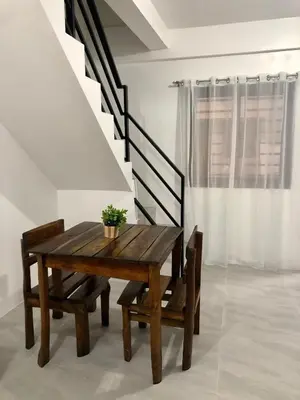 a wooden table and chairs in a room with stairs at Sebastian’s Crib F in Dasmariñas