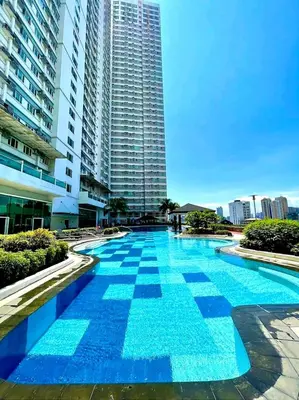 a large blue swimming pool in front of a tall building at Sea-Sky Perch Suite in Manila