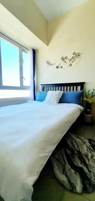 a bedroom with a large white bed with a window at Sea-Sky Perch Suite in Manila