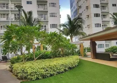 a garden in front of a building with palm trees at simple and affordable staycation at SHORE RESIDENCES in Manila