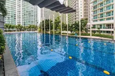 a large blue swimming pool with buildings in the background at Cozy 1BR cityview with Balcony and near Airport in Manila