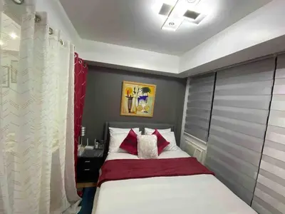 a bedroom with a bed with red and white pillows at Cozy 1BR cityview with Balcony and near Airport in Manila