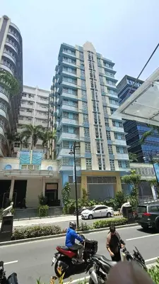 two people riding motorcycles on a city street with a tall building at 101 Newport Boulevard near NAIA Terminal 3 in Manila