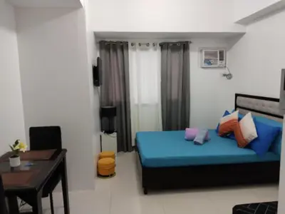 a bedroom with a blue bed and a table and a desk at Grand Riviera Suites, US Embassy Comfy, Affordable Studio in Roxas Blvd, Ermita Manila in Manila
