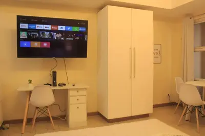 a room with a desk and a tv on the wall at A2J Luxury Studio Near Venice Mall BGC Taguig in Manila