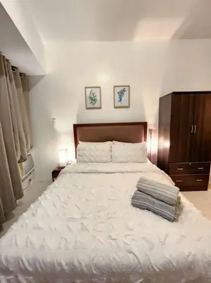a bedroom with a large white bed with two pictures on the wall at Modern Hotel-type Studio near Greenbelt Netflix 100mbps in Manila