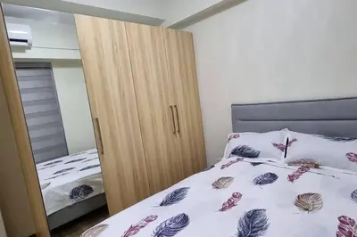 a bedroom with a wooden cabinet next to a bed at A cozy 2 bedroom condo in Metro in Manila