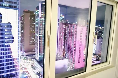 a window with a view of a city at night at Kan Emilio Cozy 1BR Apartment in Makati in Manila