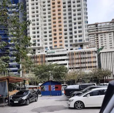 a parking lot with cars parked in front of tall buildings at Kan Emilio Cozy 1BR Apartment in Makati in Manila