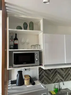a kitchen with a microwave and some wine glasses at Muji-Inspired hōme-tél in the heart of Makati in Manila