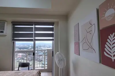 a bedroom with a window with a view of a city at Apartment in Pasig in Manila