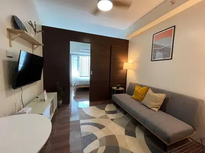 a living room with a couch and a flat screen tv at Hygge home with Ayala CBD Makati view! NEW! in Manila