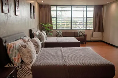a hotel room with two beds and a large window at Tropical Poolhouse QC in Manila