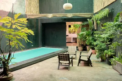 a patio with a pool and two chairs and a table at Tropical Poolhouse QC in Manila