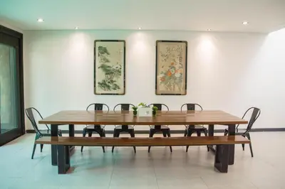 a dining room table with chairs and paintings on the wall at Tropical Poolhouse QC in Manila