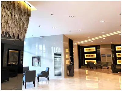 a lobby with chairs and tables in a building at Iona Reign's Vacation Unit at FAME Residences in Manila
