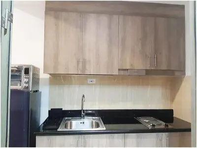 a kitchen with a sink and wooden cabinets at Iona Reign's Vacation Unit at FAME Residences in Manila