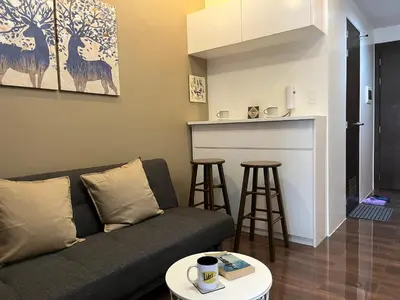 a living room with a couch and a kitchen at Homey 1 Bedroom Unit at Air Residences in Manila