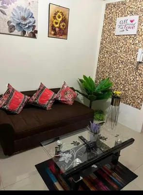 a living room with a brown couch and a glass table at Shore 1 Residences Staycation By Ms Chona in Manila