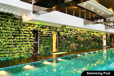 a swimming pool in a building with a green wall at the Gramercy Residences in Manila