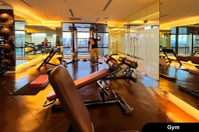 a gym with several tread machines and a man in the mirror at the Gramercy Residences in Manila