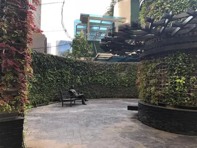 a person sitting on a bench in a garden at the Gramercy Residences in Manila