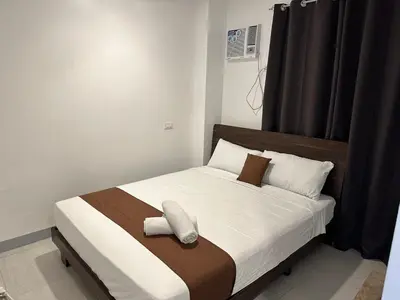 a bed with brown and white sheets and pillows at Aden Hotel in Manila
