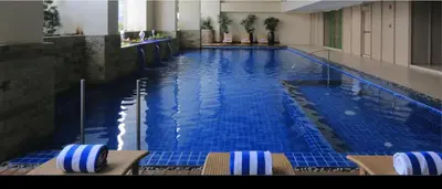 a large swimming pool with chairs in a hotel room at One bedroom Apartment with Netflix at Greenbelt Makati in Manila