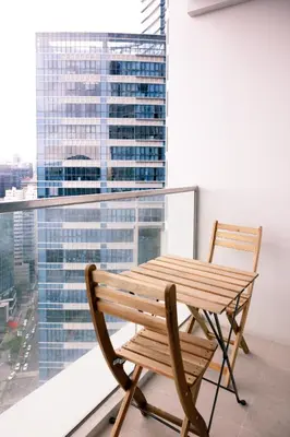 a wooden bench and chair on a balcony with a window at Uptown Parksuites Apartments Tower 2 BGC by PH Staycation in Manila