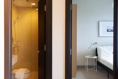 a bathroom with a shower and a toilet and a bed at Uptown Parksuites Apartments Tower 2 BGC by PH Staycation in Manila