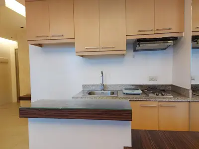 a kitchen with wooden cabinets and a sink at Romantic 1 Bedroom with Pool in Manila