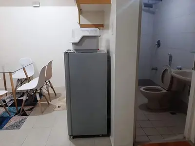 a bathroom with a toilet and a refrigerator with a printer on top at Comfy Bunkbeds at BSA in Manila