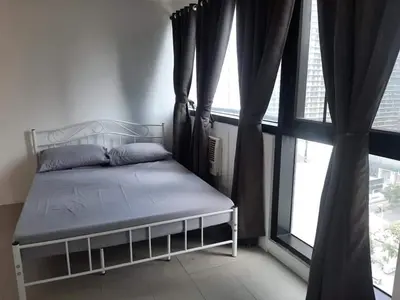 a bed in a room with a large window at Spacious 2 Bedroom Unit with Pool in Manila