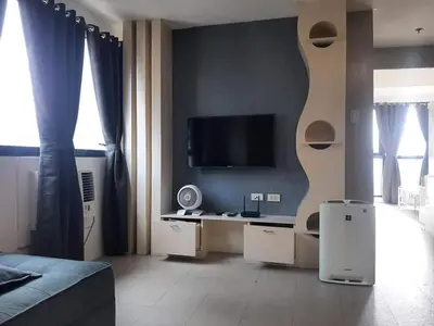 a living room with a couch and a tv in a room at Spacious 2 Bedroom Unit with Pool in Manila