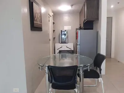 a glass table and chairs in a kitchen with a refrigerator at Spacious 2 Bedroom Unit with Pool in Manila