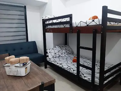 a room with two bunk beds and a table at Posh Beds with City View and Pools in Manila