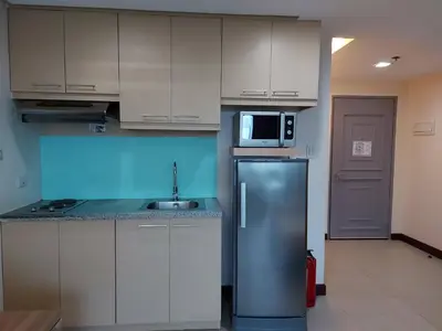 a kitchen with a refrigerator and a microwave at Posh Beds with City View and Pools in Manila