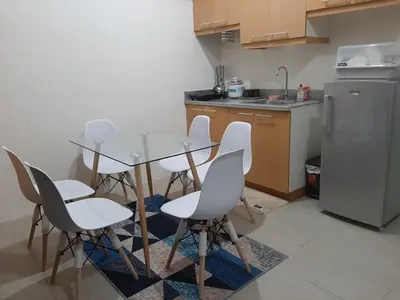 a kitchen with a table and chairs and a refrigerator at Posh Beds with City View and Pools in Manila