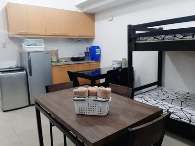 a kitchen with a wooden table with chairs and a refrigerator at Posh Beds with City View and Pools in Manila