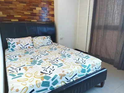 a bedroom with a bed with a blue and white comforter at Posh Beds with City View and Pools in Manila